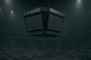 A large indoor arena scoreboard viewed from the stands, empty seats visible below